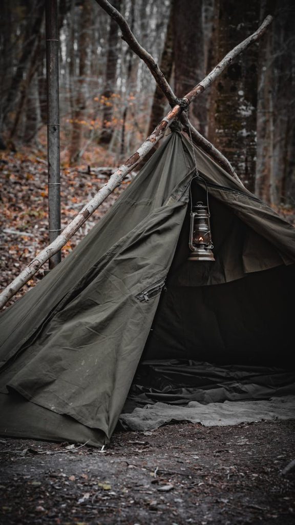 A rustic tent with an oil lamp in a serene İstanbul forest setting.