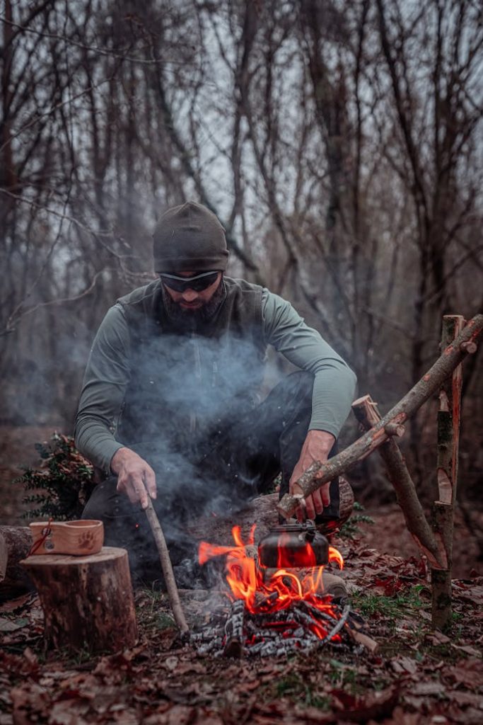 pexels photo 29949911 A man skillfully builds a campfire in a dense forest, showcasing survival techniques.